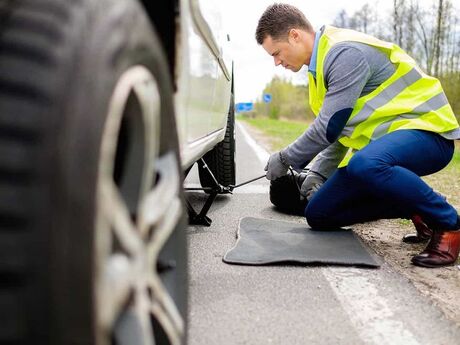 A picture of a technician replacing a flat tire. 